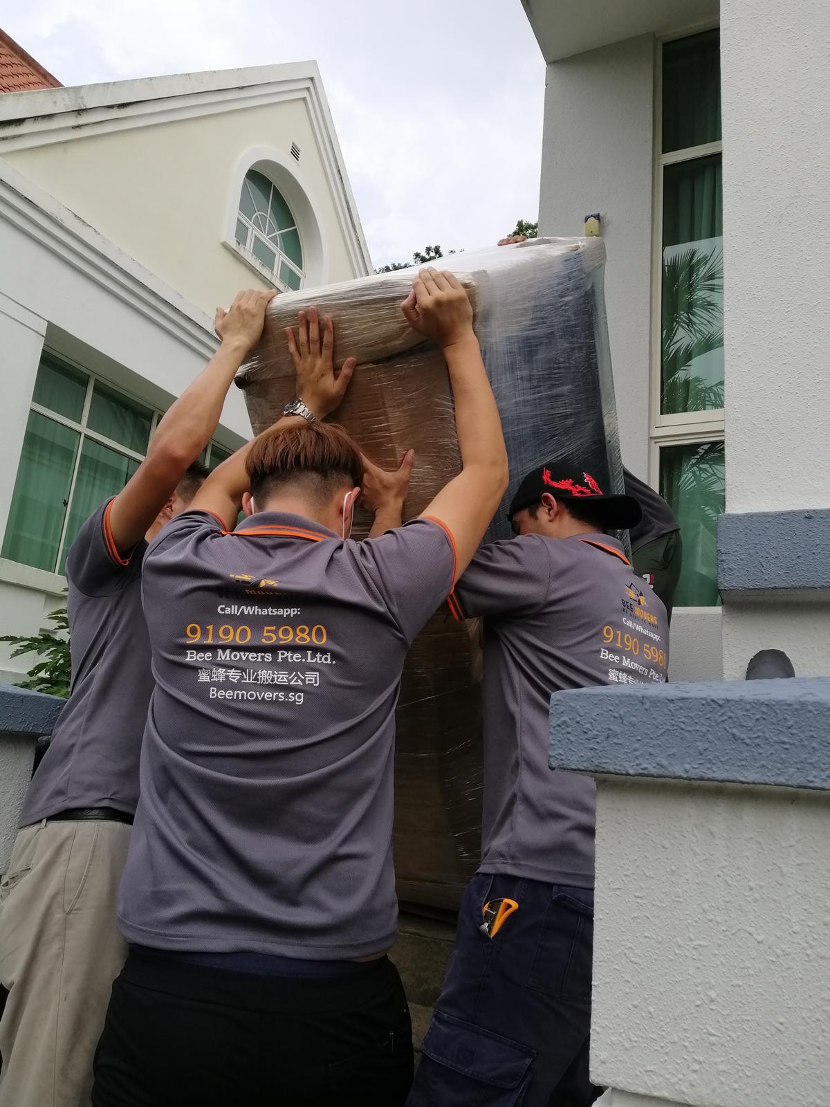 two expert movers from the Bee Movers team are moving a sofa to an apartment to another house from the transportation lorry in Bee Movers service areas. Bee Movers is the best mover company in Singapore providing the best moving service